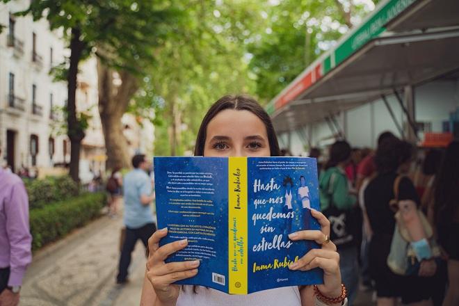 Una chica sostiene un libro en el feria granadina. 