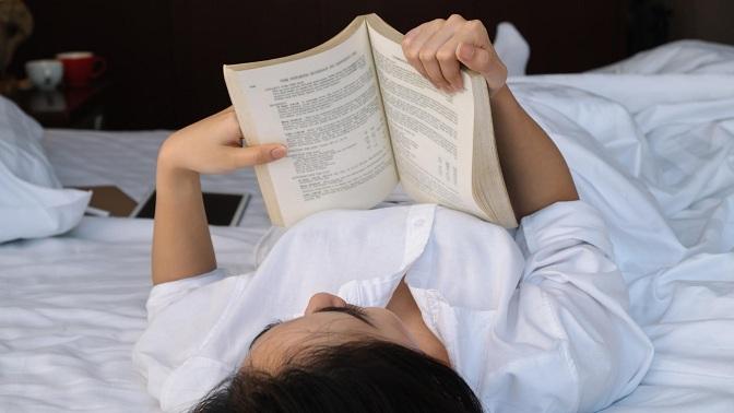 Una mujer lee en la cama. 