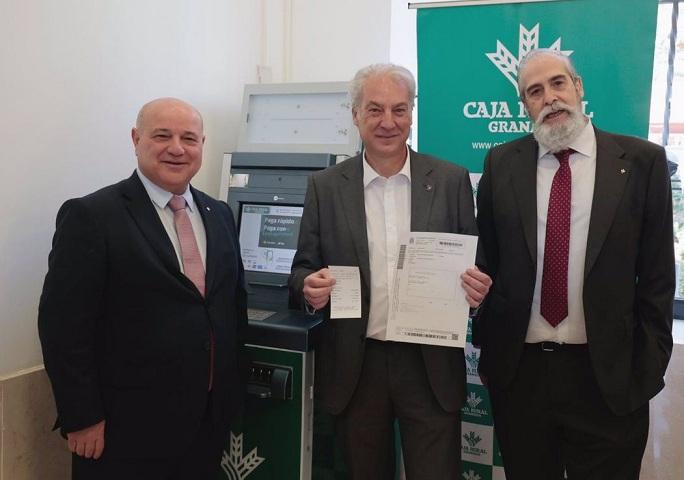 El concejal José Antonio Huertas muestra un documento de pago frente al nuevo cajero.