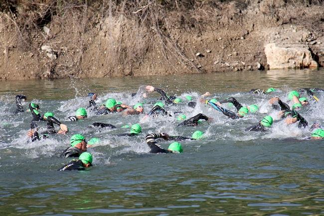 Triatletas nadando en el pantano de Canales.