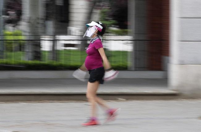 Una mujer embarazada pasea con visera y mascarilla de protección en una imagen tomada en Madrid. Sanidad recomienda administrar heparina a mujeres embarazadas para evitar trombos.