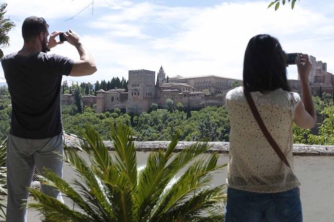 Turistas fotografían la Alhambra en un mirador.
