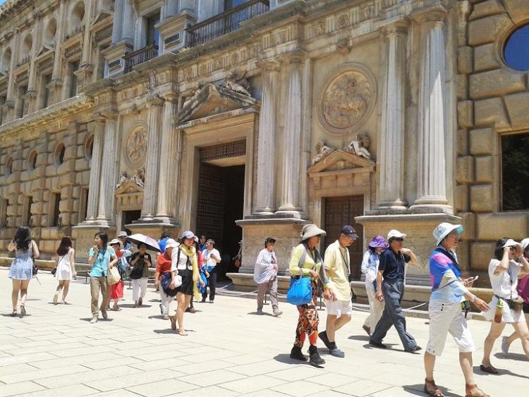 Turistas por la Alhambra se protegen del sol en verano.