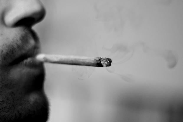 Una persona fuma un cigarrillo de marihuana. 