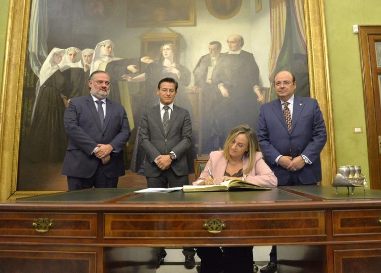 La consejera firma en el libro de honor del Ayuntamiento de Granada en presencia del alcalde, el primer teniente de alcalde y el delegado de la Junta.