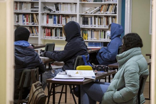 Estudiantes con abrigos recibiendo clases en una imagen de archivo.