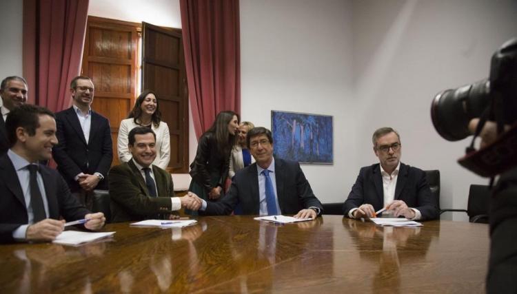 Juan Manuel Moreno y Juan Marín se dan la mano tras la firma en presencia de representantes de su partido.