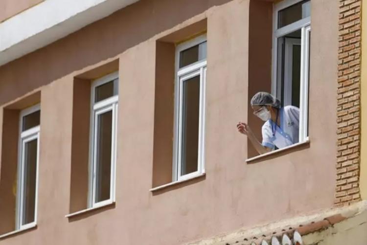 Una trabajadora se asoma a un ventanal en residencia de personas mayores.