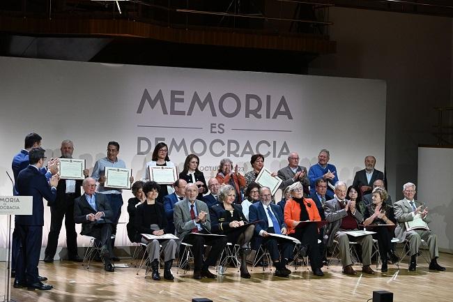 El persidente y el ministro de Presidencia aplauden a las personas homenajeadas.