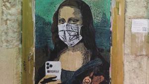 Graffiti en Barcelona del artista cubano Tvboy de la Mona Lisa, con mascarilla y móvil 