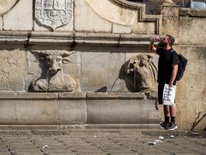 Una persona bebe agua junto a la fuente del Pilar del Toro, en la plaza de Santa Ana.