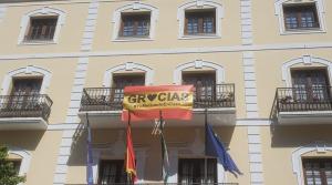 Bandera de España con la palabra 'Gracias' en la fachada municipal.