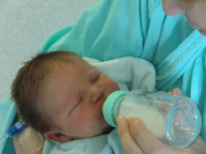 Un recién nacido toma leche de un biberón.