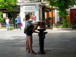 Una joven bebe agua en una fuente. 