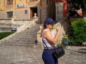 Una chica, protegida con una gorra, come un helado por el entorno de Plaza Nueva. 