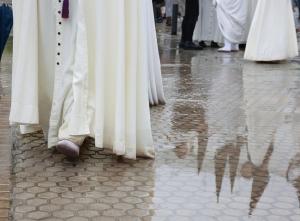 Nazarenos reflejados en un charco provocado por la lluvia. 