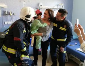 La pequeña Elena sonríe con el casco de bomberos. 