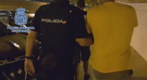 Un agente lleva a uno de los detenidos. 