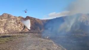 Un helicóptero descarga agua en la zona afectada por el fuego.
