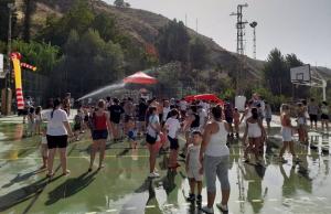 Jóvenes se refrescan en una pista deportiva de Monachil. 