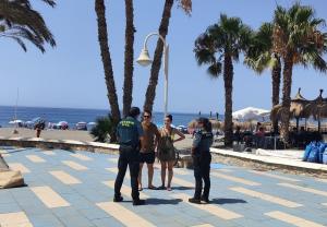 Dos agentes conversan con una pareja en la costa.