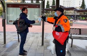 Un voluntario de Protección Civil entrega una mascarilla en la Caleta. 