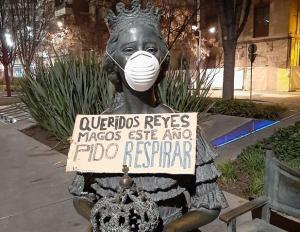 Una de las estatuas del bulevar de Constitución, con mascarilla y cartel de protesta.
