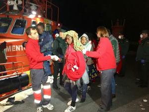 Voluntarios de Cruz Roja atienden a las personas rescatadas, entre ellas un niño.