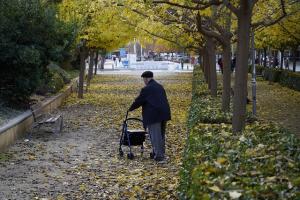 Una persona mayor camina con el suelo lleno de hojas en el parque de la antigua cárcel. 