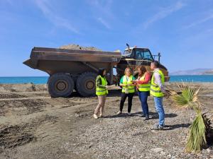 Autoridades, delante de un camión que deposita sedimentos en la playa de Melicena. 
