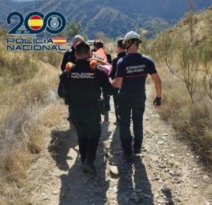 Policías y bomberos trasladan al ciclista herido en una camilla.