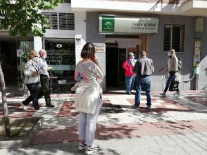 Peatones caminan junto a usuarios del centro de salud Manuel de Góngora, que aguardan su turno a las puertas del recinto.