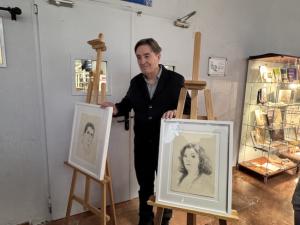 Luis García Montero con los retratos realizados por Juan Vida.