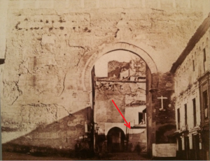 Foto anterior a 1879. Al fondo se ve la desaparecida puerta de la Alhacaba. La flecha marca donde estuvo la placa con el poema en latín.