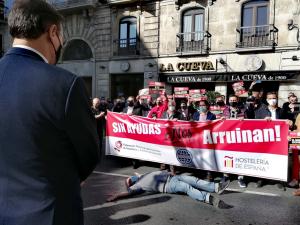 El alcalde observa a uno de los participantes en la manifestación simulando 'la muerte' de la hostelería por el cierre.