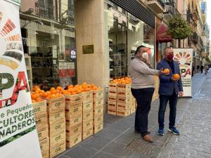 Reparto de naranjas en una calle comercial del centro. 