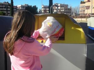 Una mujer introduce una bolsa en el contenedor de envases. 