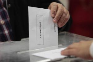 Un elector deposita un sobre electoral en una urna.