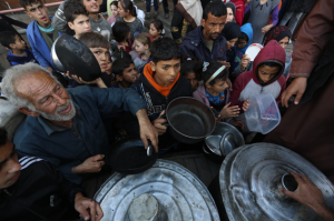 Palestinos desplazados esperan para recoger alimentos en un punto de distribución cerca de una escuela convertida en refugio.