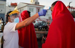 Un voluntario de Cruz Roja toma la temperatura a migrantes a su llegada al Puerto de Motril.